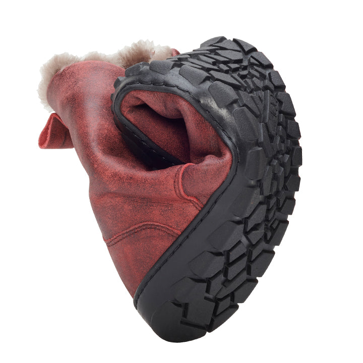 The QUINTIC Winter Velor Red Boot from ZAQQ Presented in a curved shape, it highlights its slip resistance and flexibility with a red suede exterior and a black textured sole. The inside appears padded with a soft, fluffy lining. The boot stands out against a plain white background.