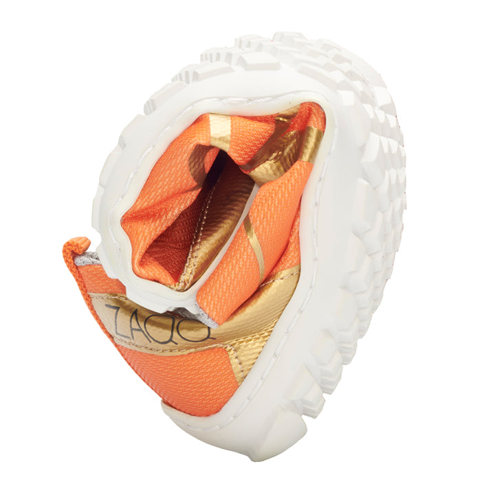 The ZAQQ SQIM Orange Gold features a flexible design with an orange-gold finish and a white textured sole, shown rolled up to highlight its pliability and exceptional comfort. The interior lining is orange with gold accents and is made from environmentally friendly recycled materials.