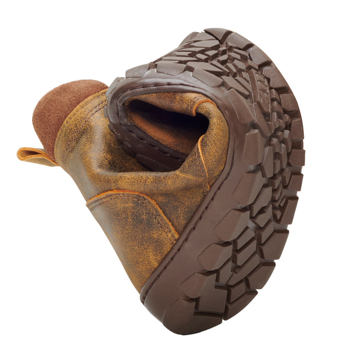 The PARQER Cognac from ZAQQ is presented rolled up in the middle, highlighting its flexibility. Featuring a textured sole and crafted from premium nappa leather, this boot exudes a worn, rugged look.