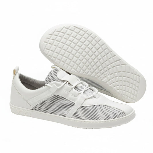 The white MCQARTER sports shoes from ZAQQ with breathable mesh details and rubber soles are issued. One shoe stands upright while the other is angled to show the profile. This highlights their precise workmanship, which offers comfort similar to that of a barefoot shoe.