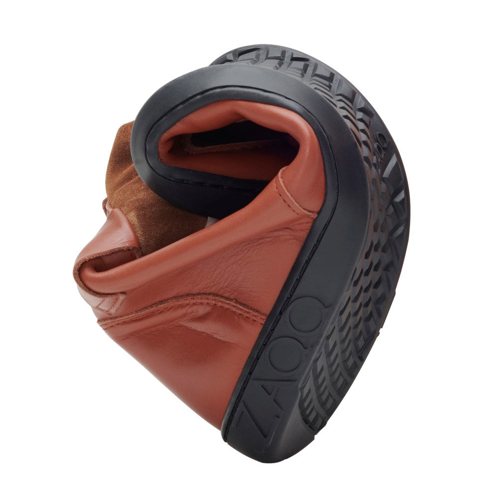 A flexible ROQA cognac boot in brown leather with a black sole that flaunts its pliability and soft texture. The textured pattern on the sole of the barefoot shoe complements this ZAQQ-Branding, creating an elegant blend of comfort and style.