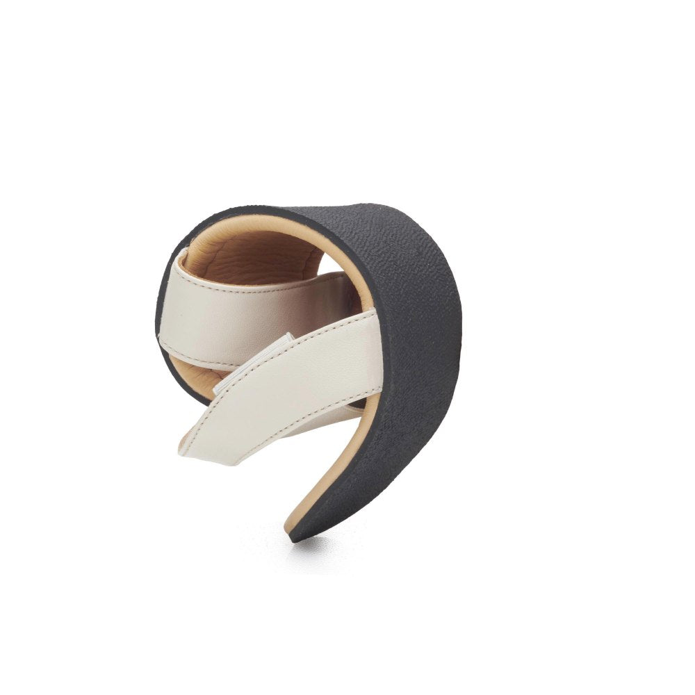 The SLIQ Beige from ZAQQ is a modern, artistic shoe with a curved black heel and a beige strap. Designed with an open, minimalist aesthetic, it features an elastic band to achieve the perfect balance between style and functionality, offering innovative design and ultimate comfort.