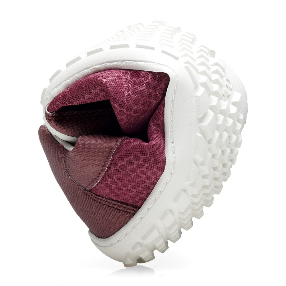 The SQIP Bordeaux from ZAQQ with flexible white textured sole is presented folded in half to highlight its flexibility. The maroon upper made from vegan materials features a mesh structure.