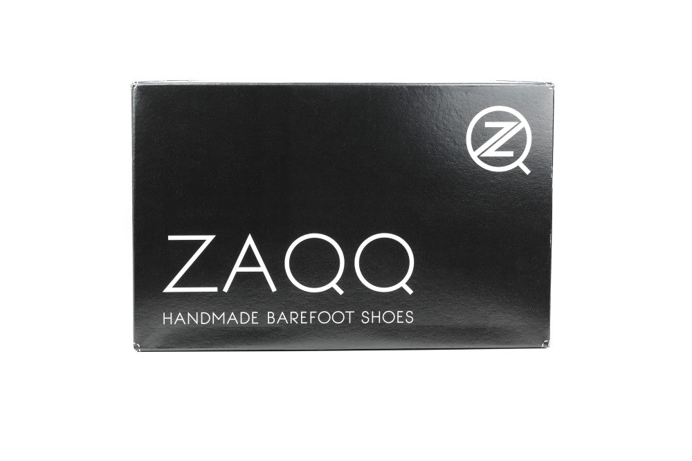 A black box with white text shows the brand ZAQQ, accompanied by the product name PEAQ Brogue Cognac. Below, the words Handmade Barefoot Shoes suggest a business casual vibe. A circular logo with a stylized Z and subtle broguing is elegantly positioned in the top right corner.