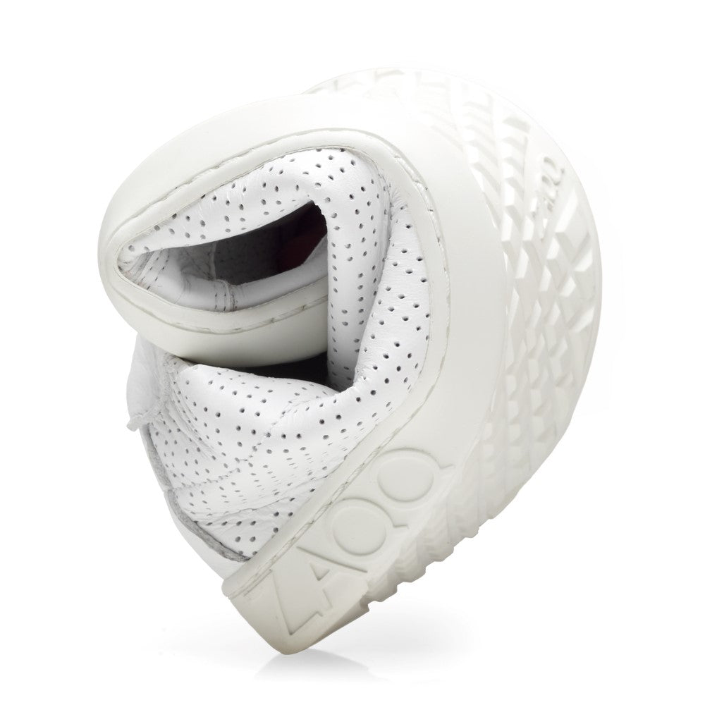 The SLOQ White Sneaker from ZAQQ is presented twisted into a ball to demonstrate its flexibility. It features a perforated upper and a textured, flexible rubber sole with embossed ZAQQlogo, highlighting its flexibility and distinctive design.