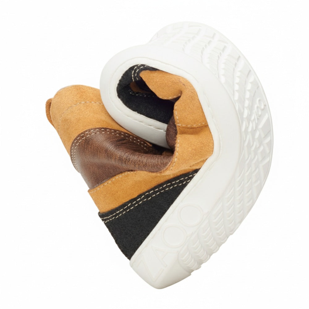 The rolled up FRANQY Brown sneaker from ZAQQ shows comfort and flexibility. Featuring a brown and black leather upper, the shoe's white sole with textured pattern and visible branding highlights its unique design. This position highlights the flexibility and comfort of the sneaker, making it ideal for those who value comfort.