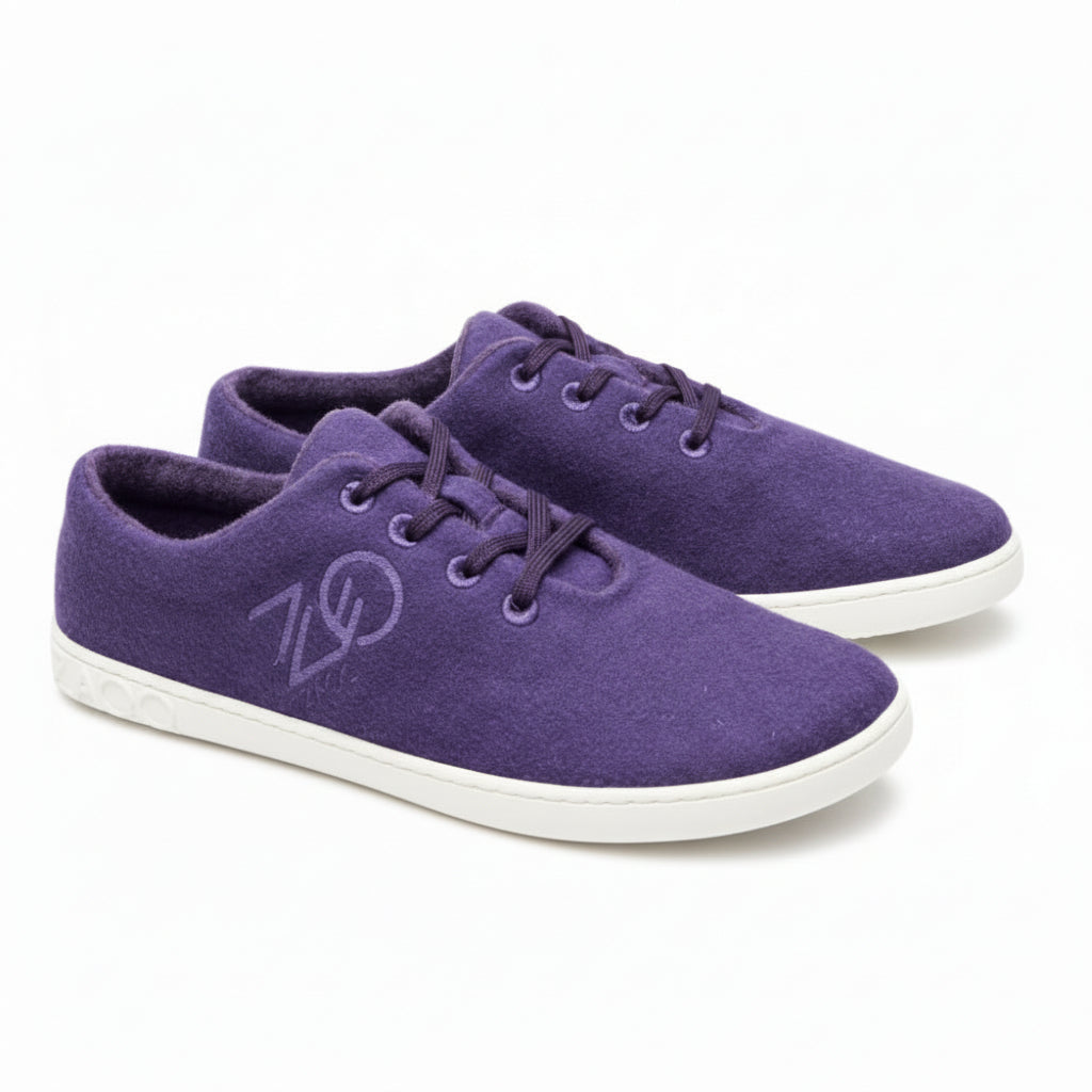 A pair of LIQE Purple sneakers from ZAQQ with white rubber soles and matching purple laces. These shoes feature a unique logo on the side and a textured design on the heel for added flair.