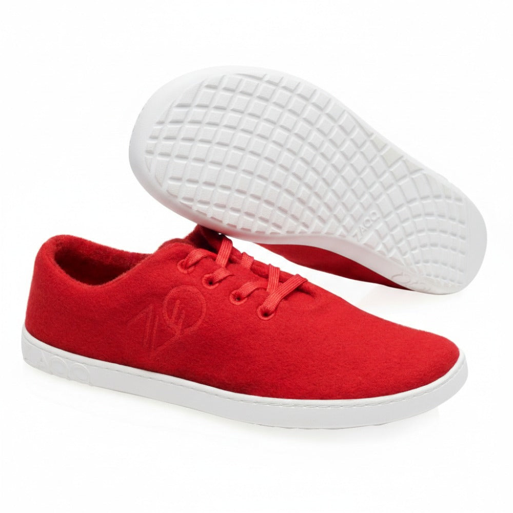 The LIQE Race Sneakers from ZAQQ are artfully presented against a white background. One sneaker lies on its side, showing off the textured gray sole, while the other stands upright. Red laces complement the fabric upper, creating a vibrant yet relaxed style.