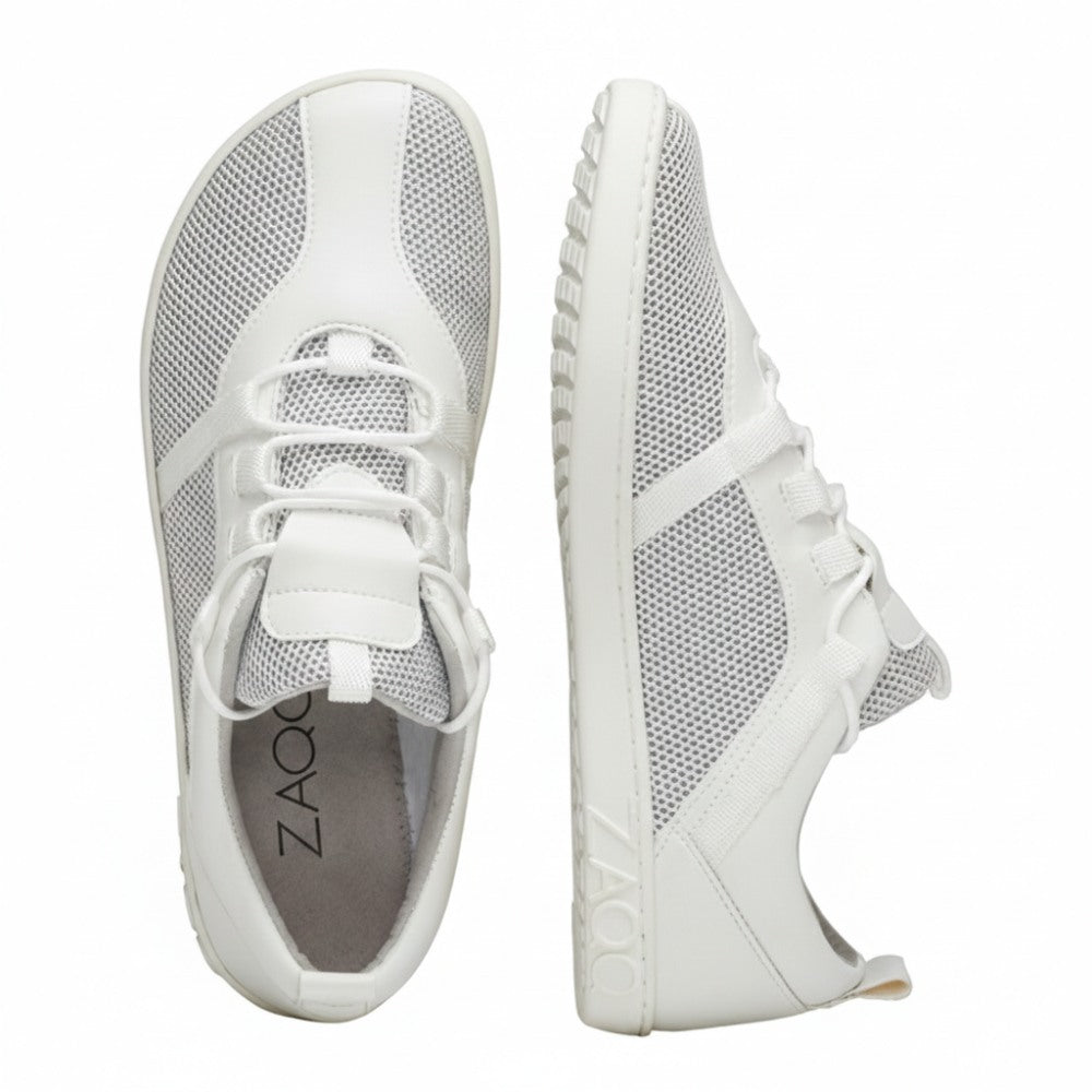 A pair of white MCQARTER sneakers with breathable mesh fabric and rubber soles, shown from above and from the side. The brand name ZAQQ is printed on the insole and sole for comfort and style.