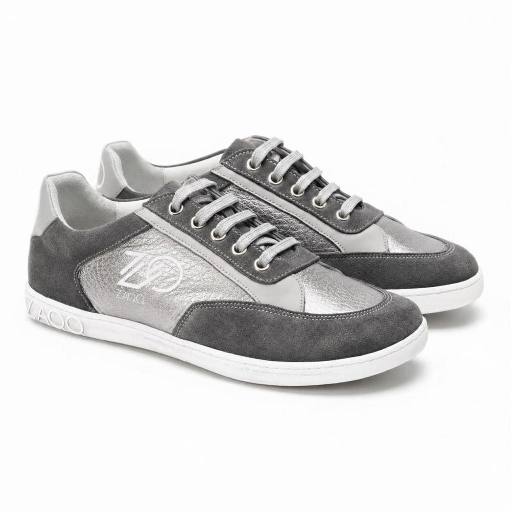 A pair of OQTAV Grey sneakers from ZAQQ, crafted from velvety suede and textured inserts. With silver laces and the distinctive Zagoo logo on the side and heel, these stylish shoes are presented side by side on a white background.