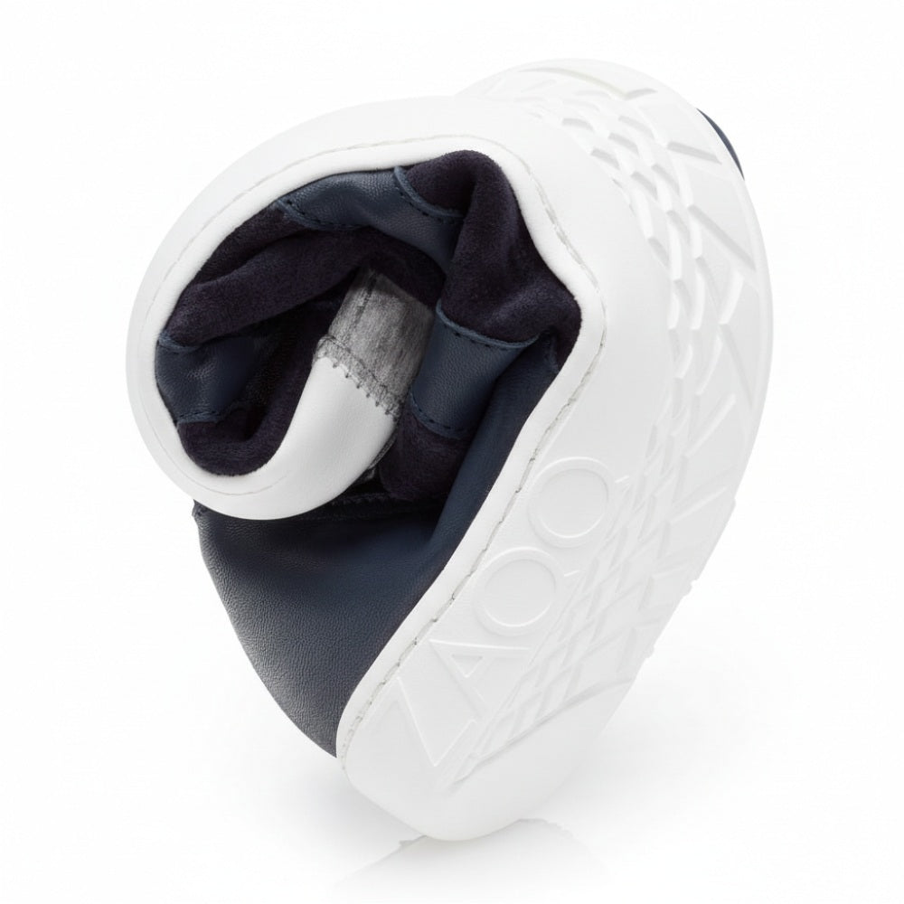 A barefoot shoe called QAANAAQ Blue by ZAQQ features a flexible sole that spirals to showcase its checkered pattern, with the letters ZAQQ can be clearly seen on the page. The dark lined interior is made of breathable material and underlines both the flexibility and the well-thought-out design.