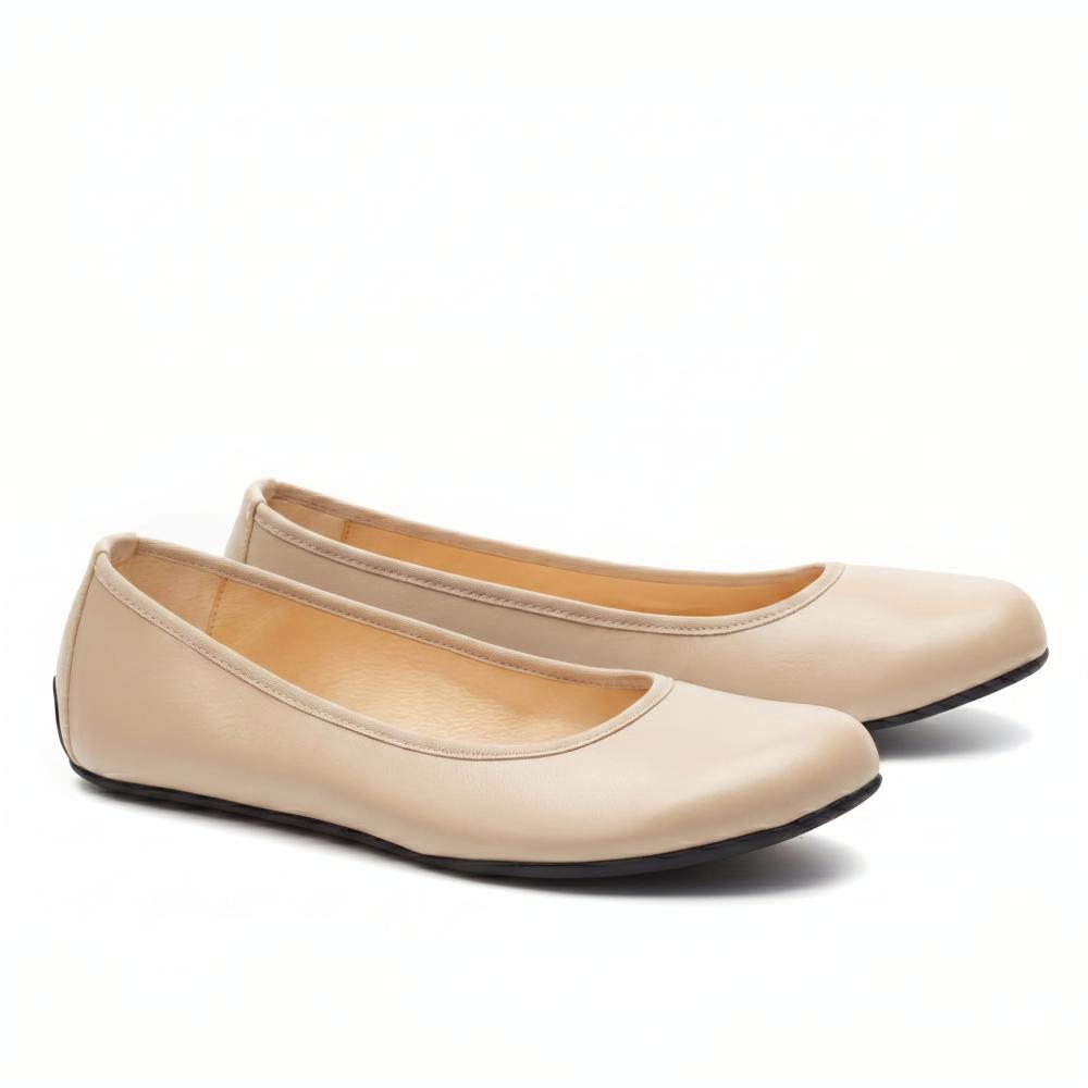 “QARMA Beige” by ZAQQ is a pair of ballerina flats in luxurious nappa leather with a rounded toe and a deep neckline on the sides, elegantly presented on a white background.