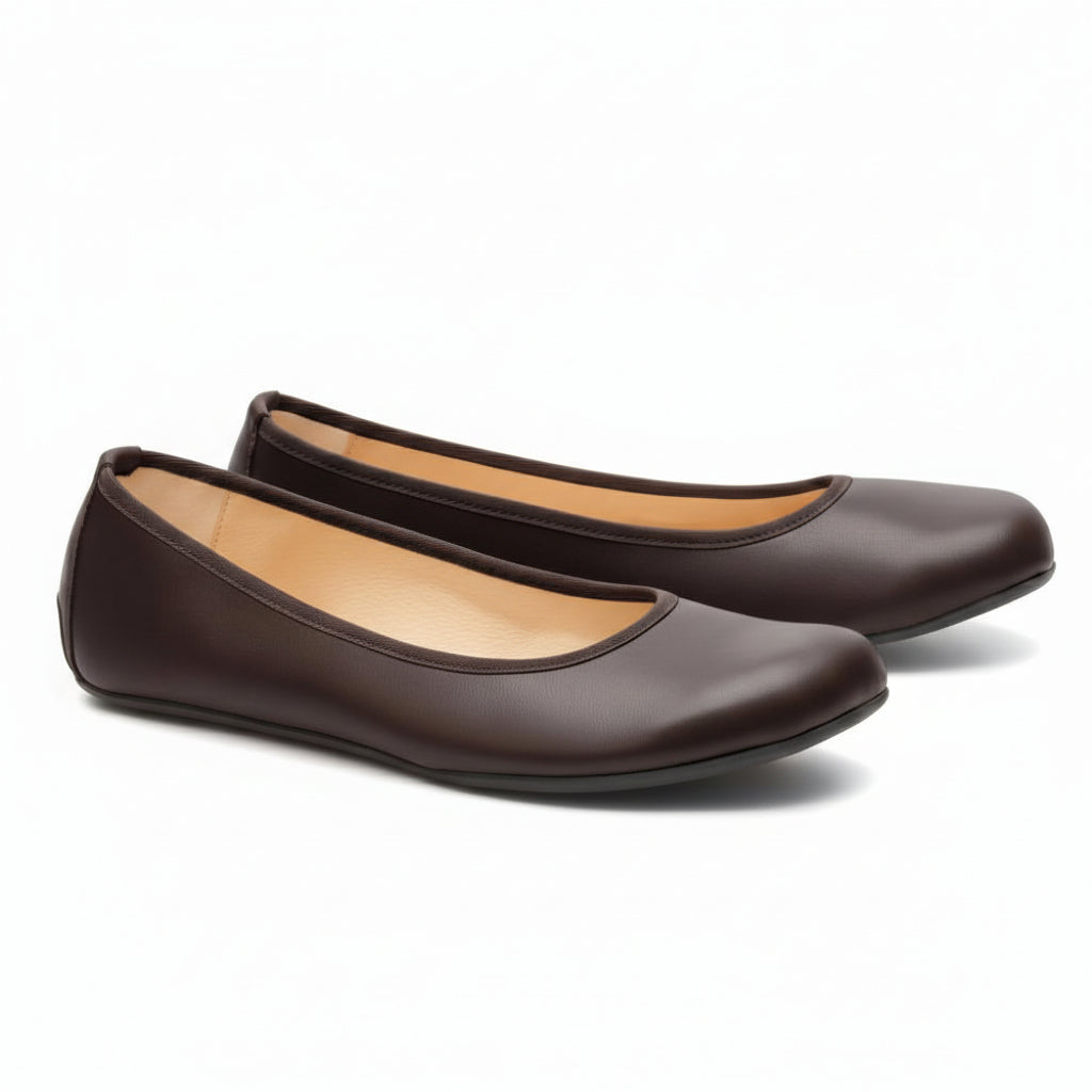 A pair of elegant dark brown QARMA ballet flats from ZAQQ, with one shoe laying on its side to reveal the sole and the other standing upright to highlight the rounded toe and low-cut design. The light brown lining gives these barefoot ballet flats an elegant touch.