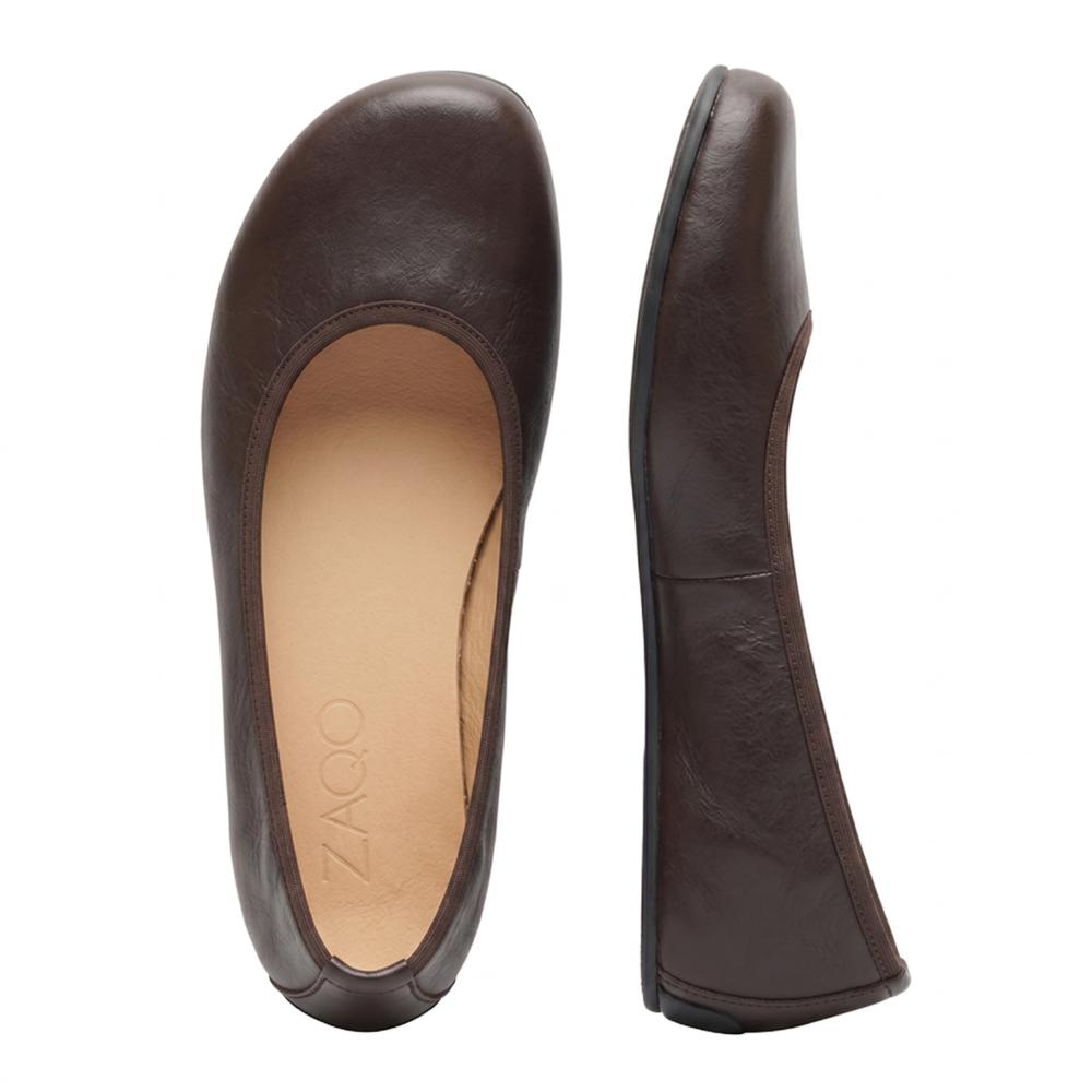 Shown is a pair of simple dark brown ballerina shoes made from luxurious nappa leather. One shoe stands upright while the other lies flat with the brand name printed on it ZAQQ shows inside. With their smooth texture and rounded toe design, these QARMA barefoot ballet flats exude both elegance and comfort.