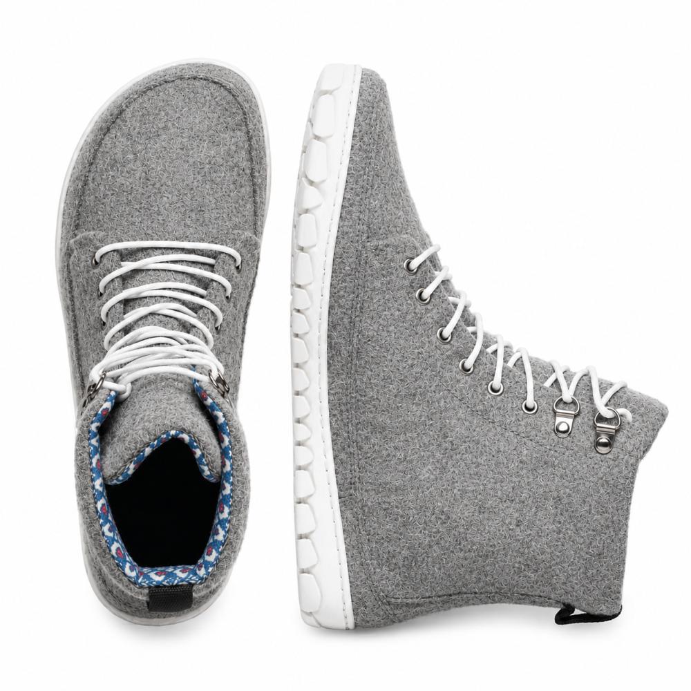 We present the QICE Grey from ZAQQ: These sneakers have a high-top design in grey with white laces and offer a good view from both the top and side. Their standout feature is a uniquely textured outdoor sole that enhances style and comfort. They are crafted from materials similar to Merino wool, offering a striking blend of comfort and fashion.
