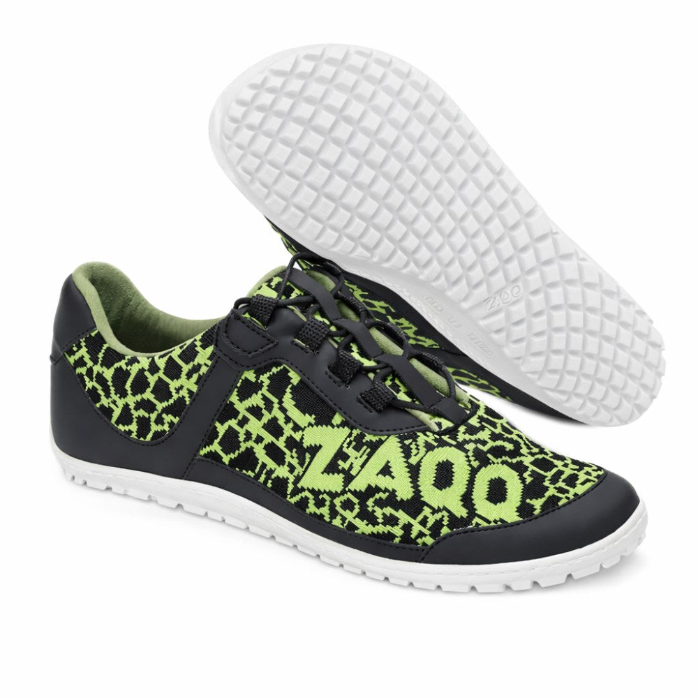 Sporty sneakers in a black and neon green pattern design with a side “ZAQQ“logo. Called QINGSTON Green, they are made from vegan materials and feature black laces and a textured sole for greater grip on a white background.
