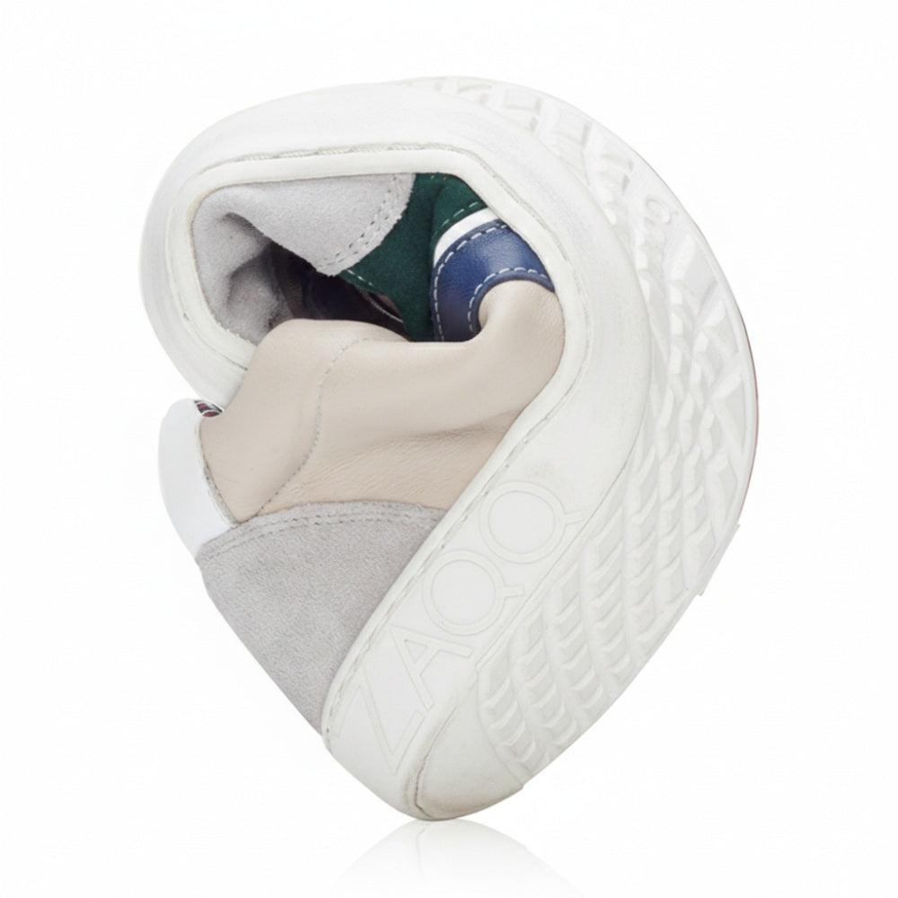 The QLAUDE Gray sneaker from ZAQQ, a men's barefoot shoe available in shades of gray, beige, white and green is presented rotated to highlight its flexibility. The word “ZOO” is on the ZAQQ-Sole visible, which has a textured pattern.