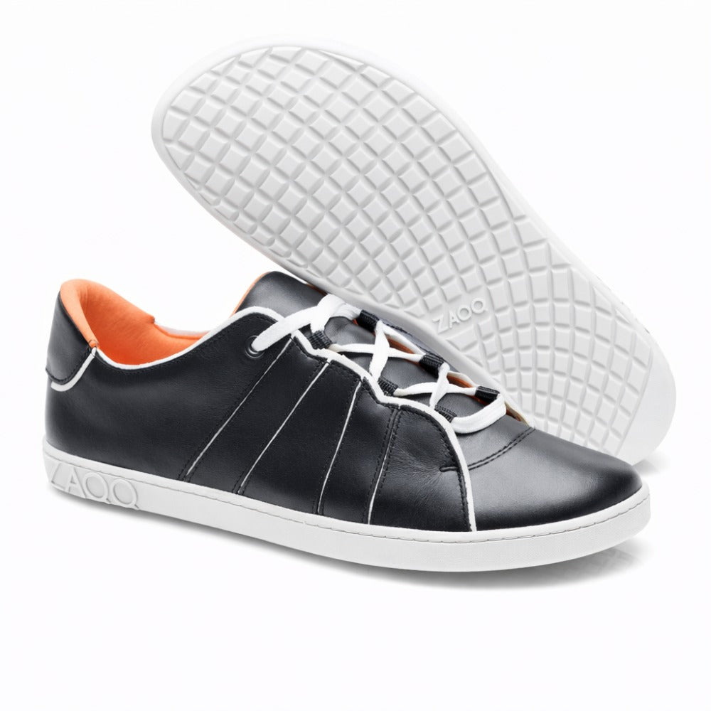We present it ZAQQ QQQ Low Black White: a pair of black leather sneakers for exceptional comfort. These barefoot shoes have white soles and laces, an orange interior and a grid pattern sole design. The elegant coinage of the word ZAQQ adorns the heel.