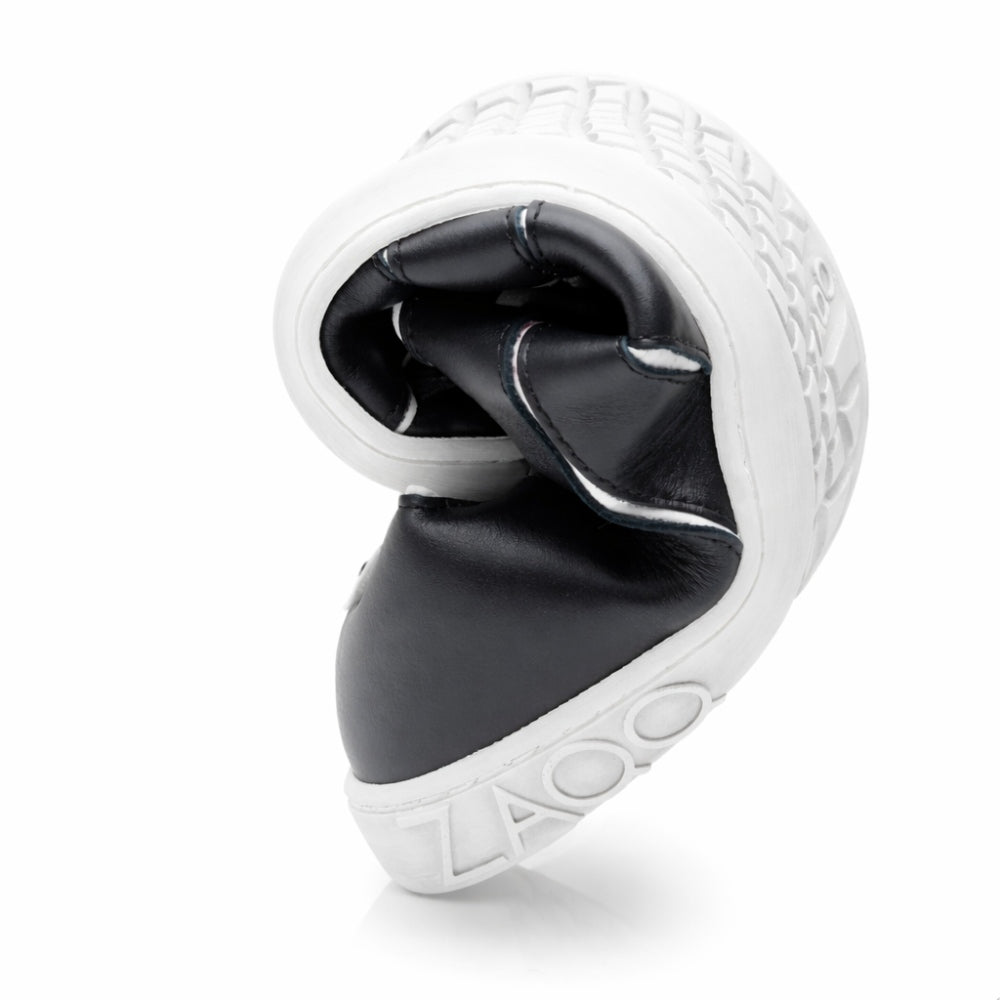The QQQ Low Black White from ZAQQ is a flexible sneaker that can be bent in the middle, which emphasizes its flexibility. Featuring a black upper with woven texture and a white sole with embossed text, it offers exceptional comfort and presents a sleek, modern design.