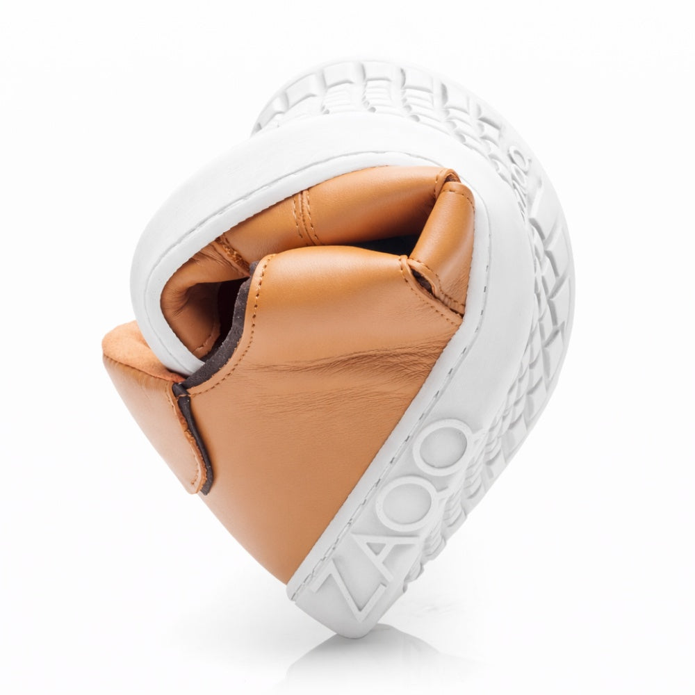 The QQQ Low Sierra, a flexible barefoot shoe from ZAQQ, features light brown nappa leather and a white sole that folds into a ball to demonstrate its flexibility. The brand name ZAQQ is embossed on the flexible rubber sole.