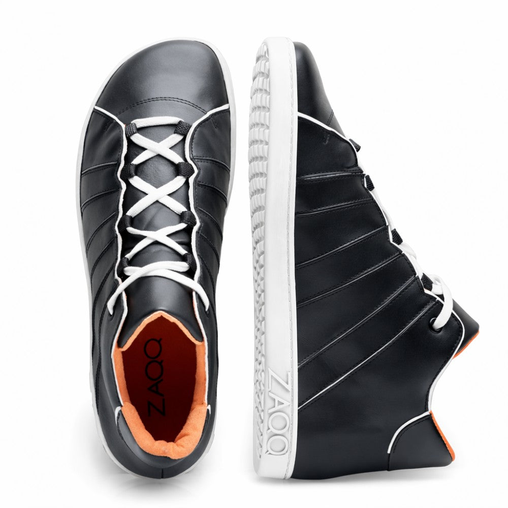 Introducing the QQQ Mid Black White from ZAQQ: a pair of elegant and modern black sneakers made of nappa leather with white laces and soles. One shoe stands upright and shows the side design as well as the ZAQQ-Branding on the inside while the other shoe is tilted to highlight its unique barefoot shoe style.