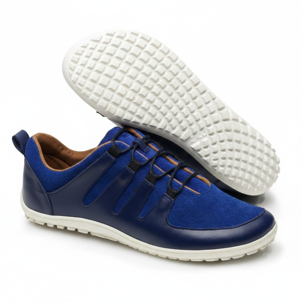 A pair of blue and navy SHOQQ Trident sneakers from ZAQQ with white rubber sole. One shoe stands upright while the other is tilted to highlight the textured sole pattern. These sneakers feature a casual and modern design and are ideal for everyday wear.