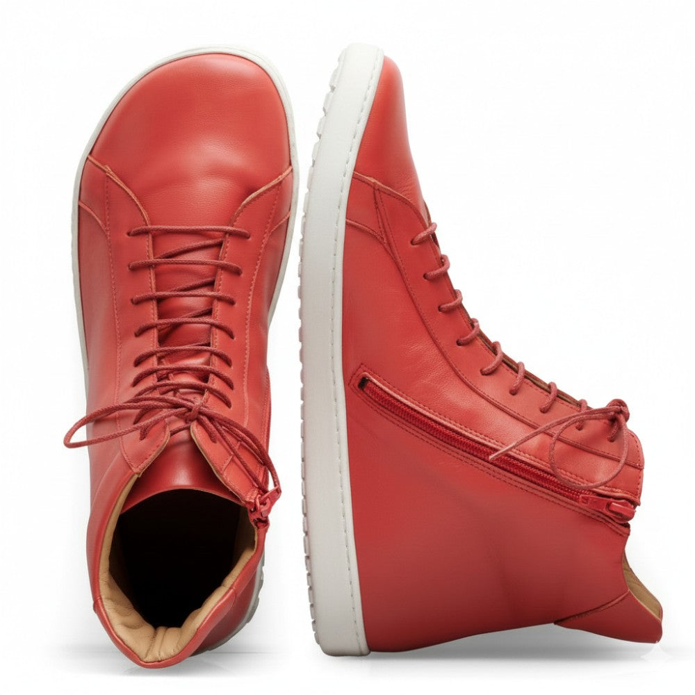 A pair of SNAQ Red sneakers from ZAQQ, Made of high-quality nappa leather, with white soles and side zippers. One shoe stands upright while the other lies on its side, highlighting the detailed insole and sole design.