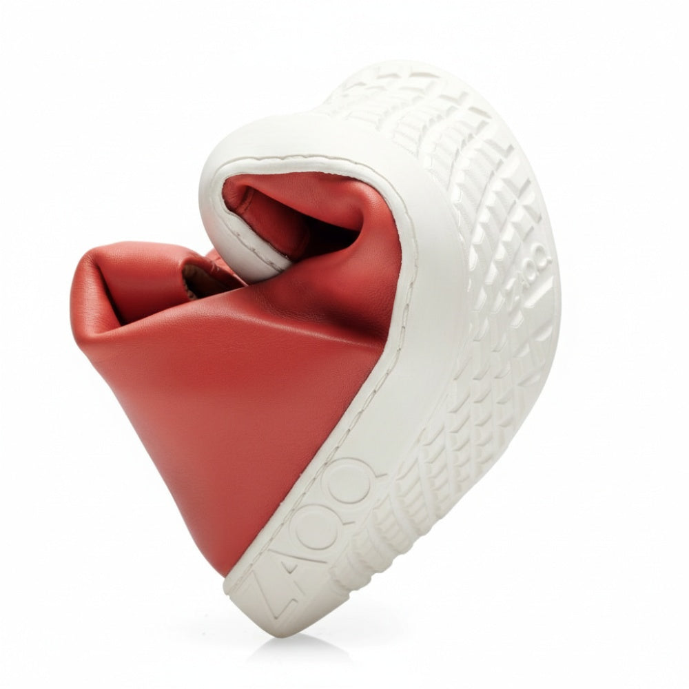 A single SNAQ Red high top sneaker is artfully twisted into a spiral, highlighting its impressive flexibility, and features a thick, textured white sole. This design with the brand name embossed ZAQQ Seamlessly combines comfort and style in an innovative way.