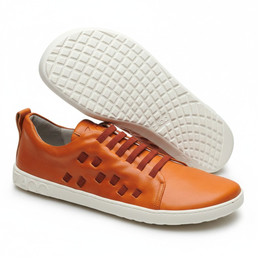 The STRAQ Sierra from ZAQQ is an orange casual shoe with square cutouts on the side and a white, checkered nappa leather sole. It feels like a barefoot sneaker and proudly displays the brand name on both the heel and sole.