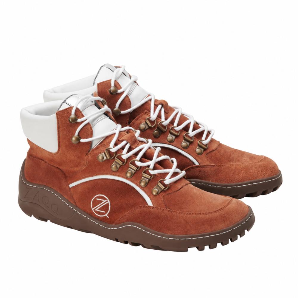 Ein Paar wasserdichte Wanderstiefel TERRAQ Cognac von ZAQQ mit Wildleder-Finish in warmem Braun mit weißen Schnürsenkeln und Akzenten um den Knöchel. Diese Barfußschuhe sind mit robusten braunen Sohlen und metallischen Ösen ausgestattet und somit ideal für Abenteuer im Freien.