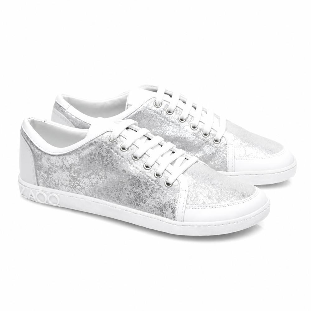 We present the TIQQ Silver White from ZAQQ: A pair of stylish sneakers made from high-quality nappa leather with a striking metallic-silver texture and white soles. These sneakers feature bright white laces, decorative stitching, and a distinctive 4000-detail on the side of the sole.